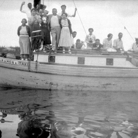 Des personnes vêtues assez simplement sont à bord d’un petit bateau.