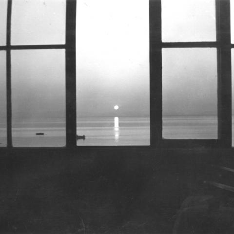 An old woman sitting at a window, watching the sun set over the St. Lawrence.