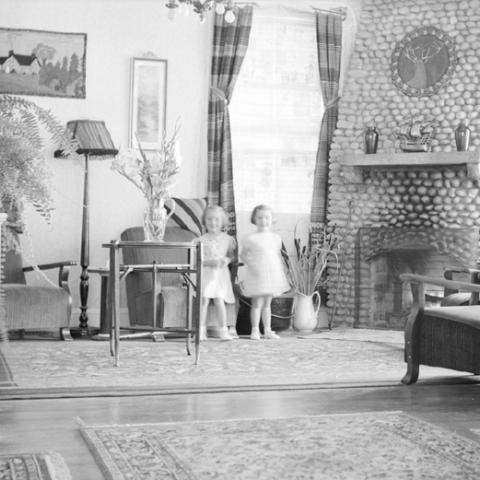 Deux petites filles en robe blanche posent dans le salon d’un hôtel.