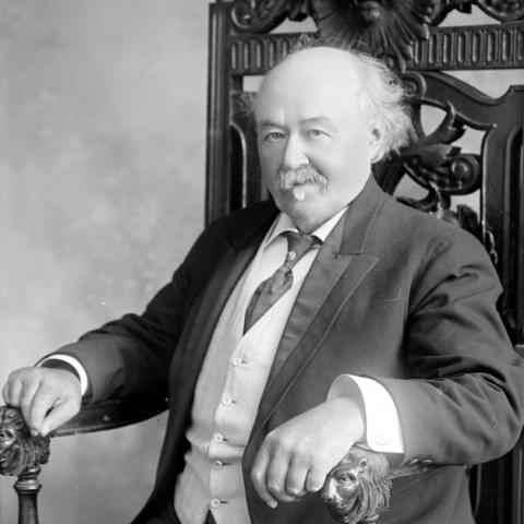 Portrait of a man sitting in a chair with lion-head armrests.