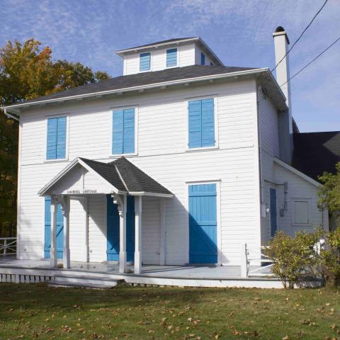 A large white house with closed blue shutters.