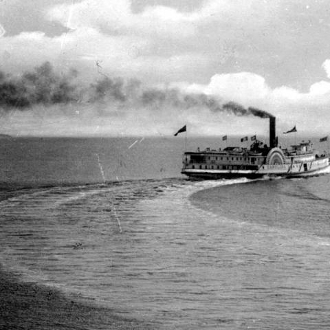 A cruise ship maneuvering, black smoke rising out of its chimney.