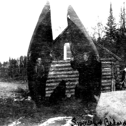 Two men carrying their canoes on their shoulders.