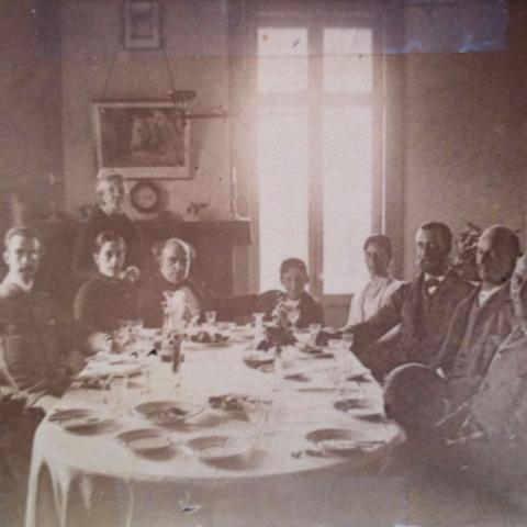 A dozen guests are seated at a dining table.