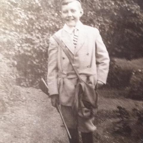 A boy in stylish hunting attire posing proudly, rifle in hand.