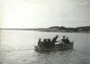 A man rows in a boat where are several summer vacationers.